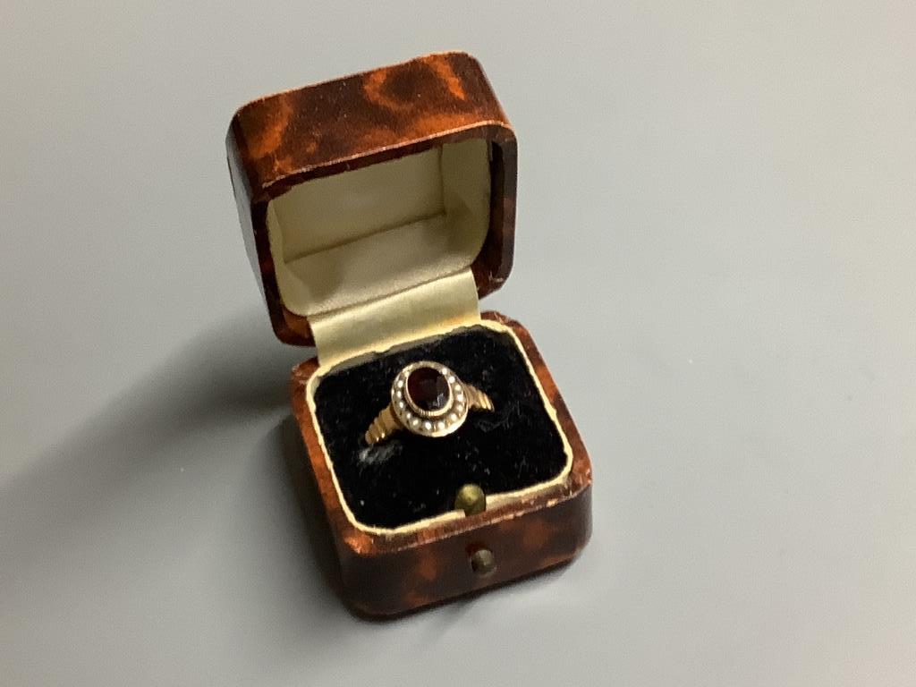 An early 20th century 9ct gold, garnet and seed pearl cluster ring, size O, gross 2 grams.